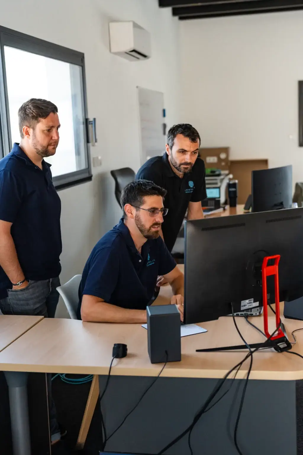 Équipe de VESTALIA en réunion, analysant des solutions domotiques sur ordinateur, mettant en avant leur expertise technique et leur engagement envers le service client.